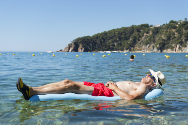 Retired man sleeping with inflatable bed floating in the sea