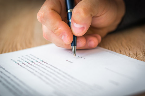 Businessman is signing a contract to conclude a deal - business concept