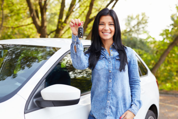 Happy woman with car keys standing by her car