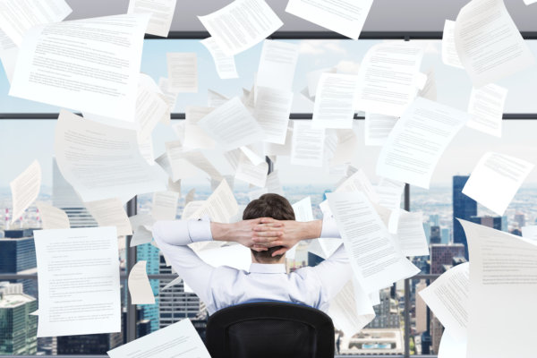 young businessman sitting in office and falling papers