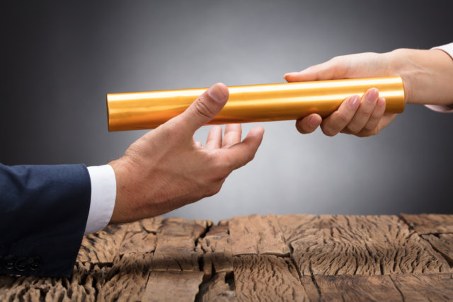 Close-up Of A Businessperson Passing Baton